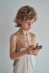 Boy with smartphone and charger glued on chest with plaster