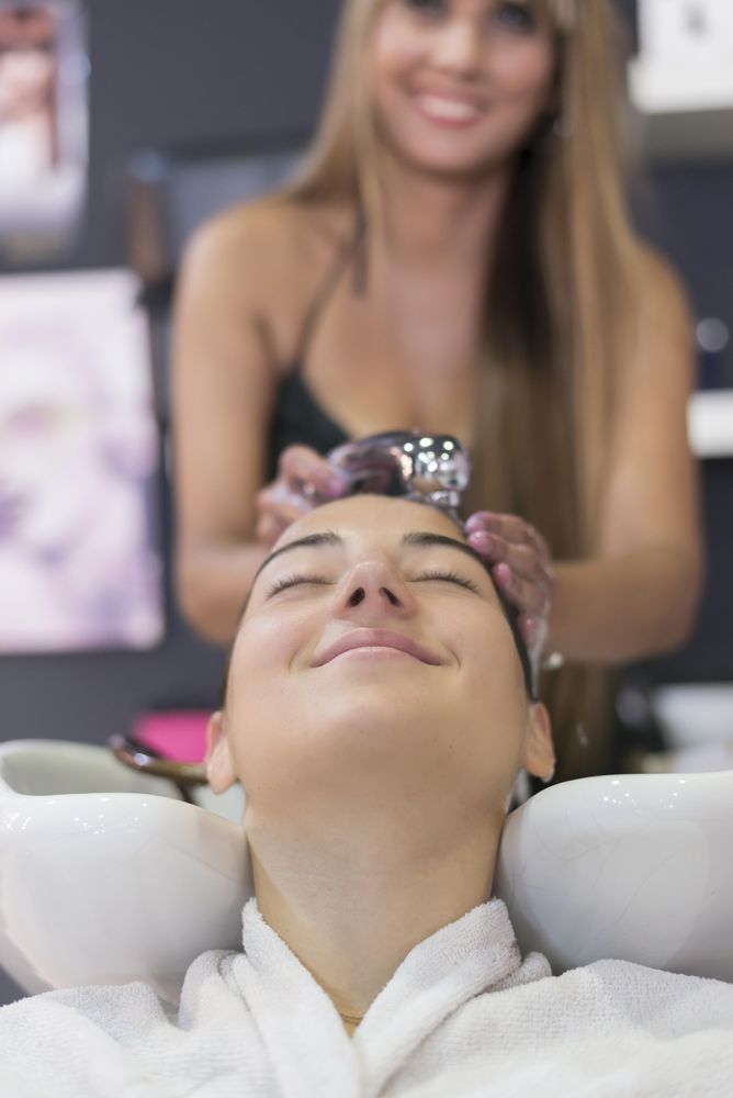 Smiling female client in hair salon having her hair washed