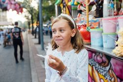 Cheerful girl eating cotton candy on street