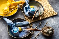 Easter holiday table setting with blue and yellow egg decorations in bowls