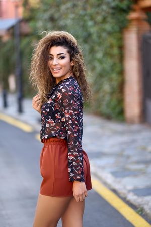 Smiling Arab woman looking back while wearing casual clothes in the street
