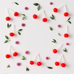 Colorful pattern made of red cherry lollipops, leaves, and flowers