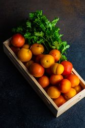 Looking down at wooden box of plums with parsley
