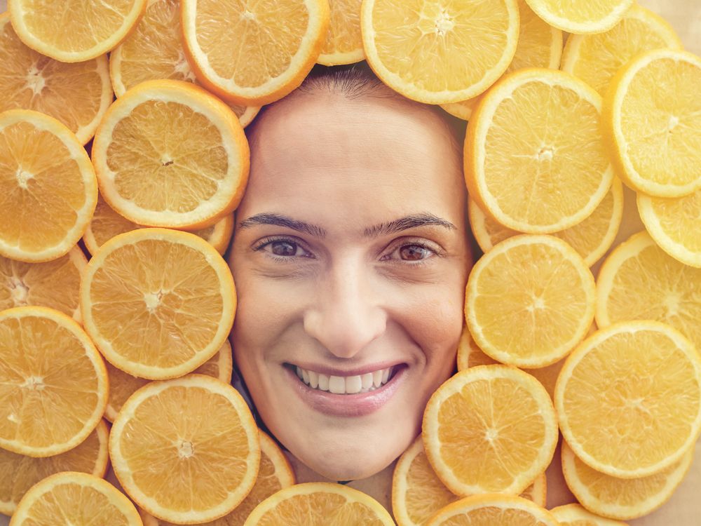 Smiling woman among slices of ripe oranges