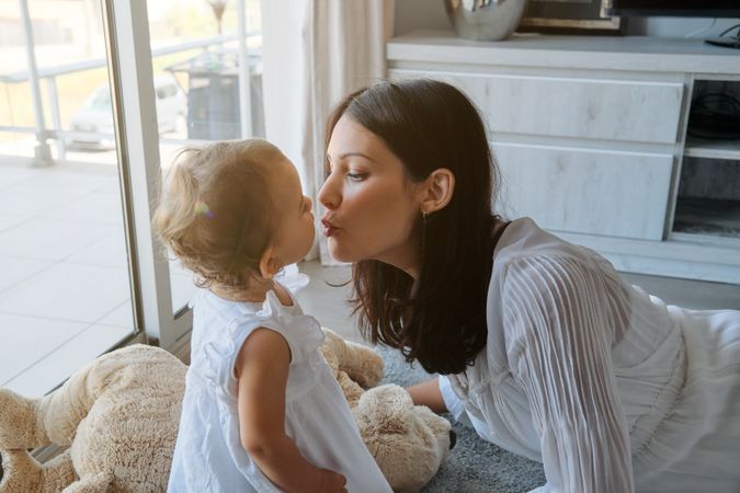 Young mother kissing daughter at home