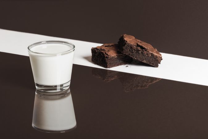 Glass of milk and chocolate brownies on blocked background