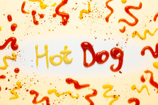 Inscription Hot dog made of sauces and spices on plain background