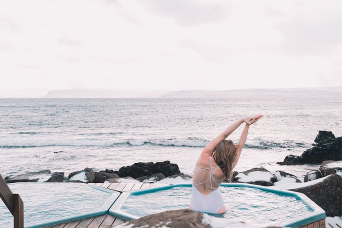 Woman sitting in pool near stones