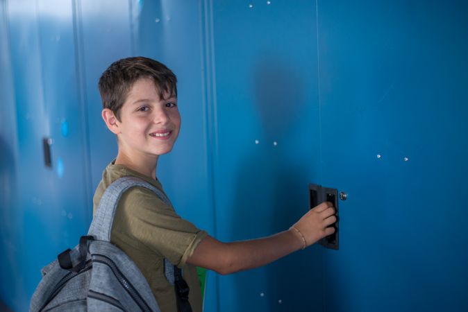 Smiling teenage boy looking around at locker