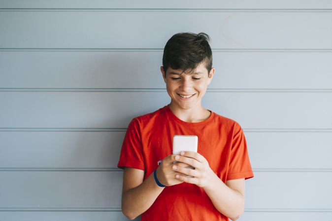 Profile of a happy male teen texting on a smart phone with copy space