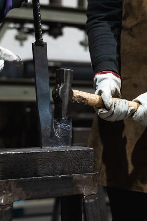Blacksmiths forging hot metal with hammer in workshop