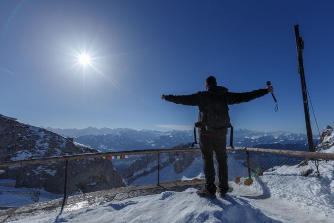 Tourist with hands apart on mountain top in sunlight