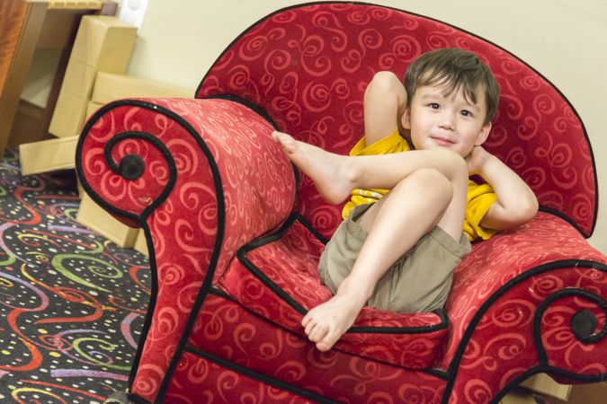 Biracial Boy Relaxing in Comfortable Red Arm-Chair