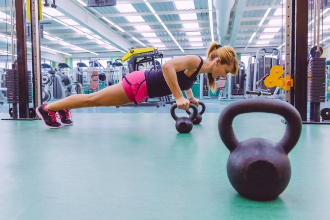 Woman doing planks with kettle bells