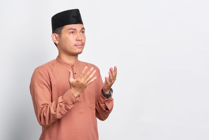 Muslim man praying in kufi head wear and looking up