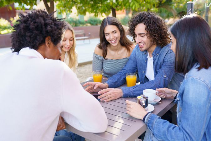 Group of friends having coffee and juice outside and talking