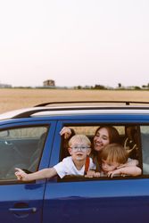 Young woman with little sons sitting in car in countryside