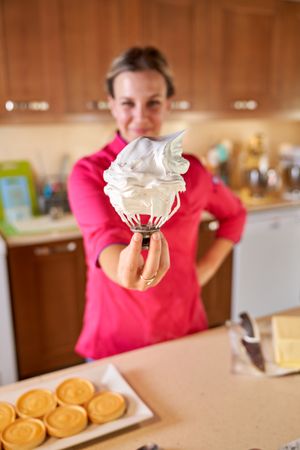 Smiling female pastry chef showing cream on mixer