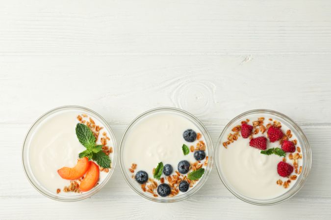 Flat lay composition with yogurt desserts and ingredients on wooden background