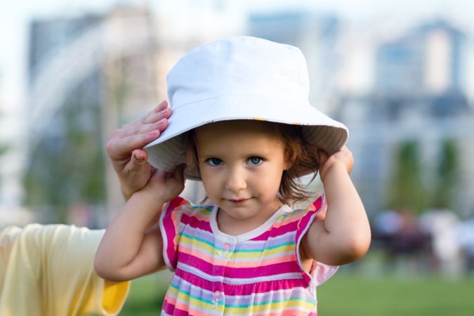 Toddler putting on summer hat
