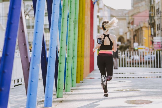 Woman with earphones running on street