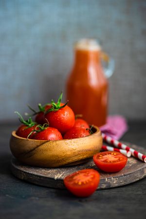 Side view of bowl of fresh tomatoes with juice in background
