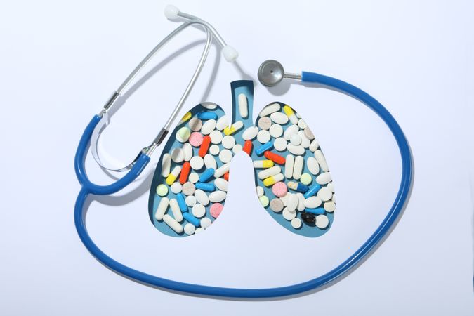 Lung shape cut out of paper with pills underneath with doctor’s stethoscope