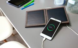 Mobile phone charging with portable solar panel over office desk