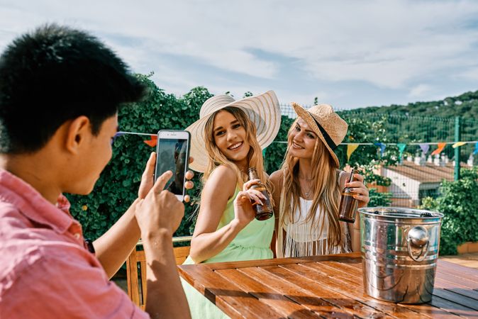a young man takes a selfie of two blond women