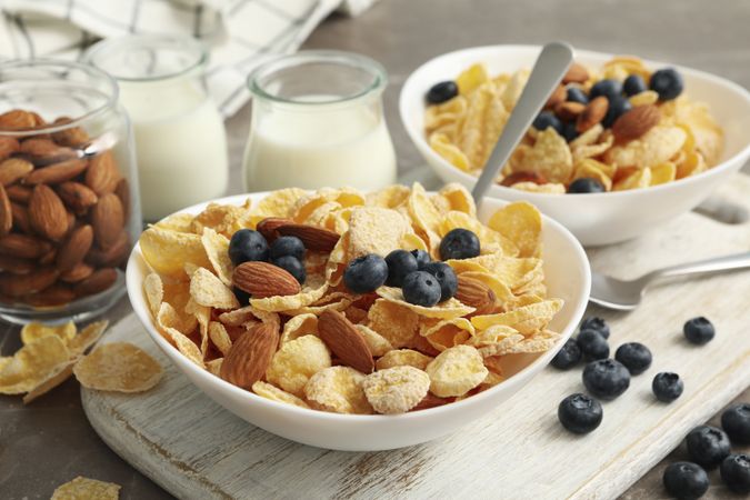 Concept of breakfast with muesli, berry, nut and milk on gray table