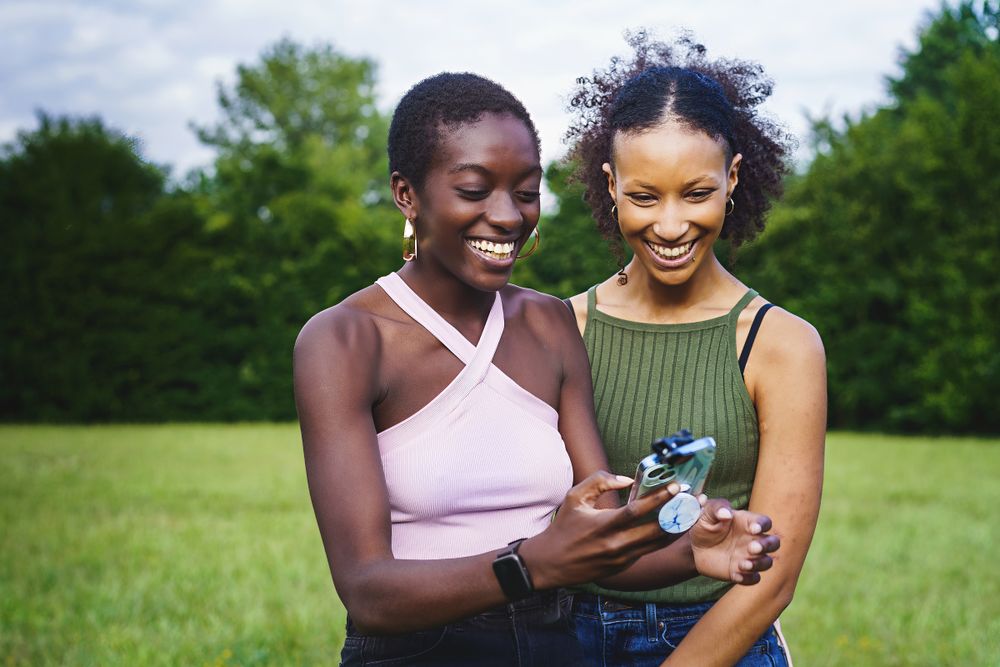 Multiracial girlfriends watching content online standing in the park