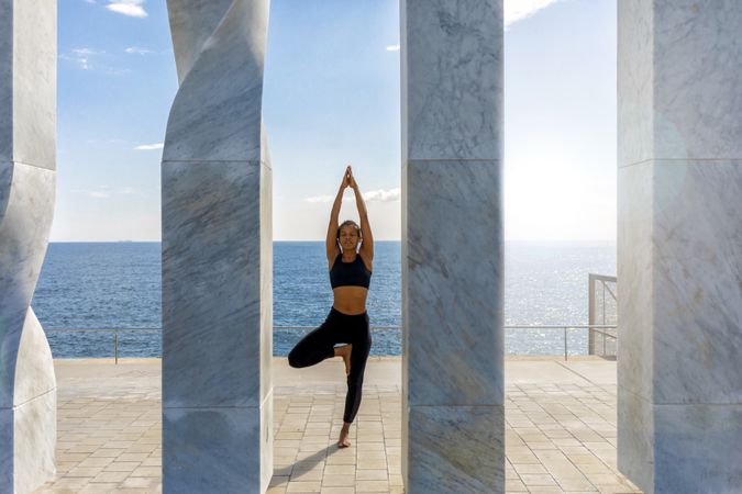 Female balancing on one leg between sculpture with ocean view 