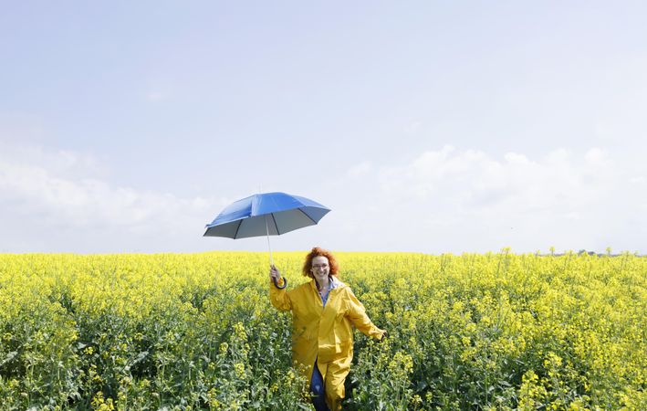 Smiling woman holding umbrella in yellow field