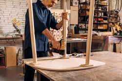 Man building table with power tools in woodworking shop