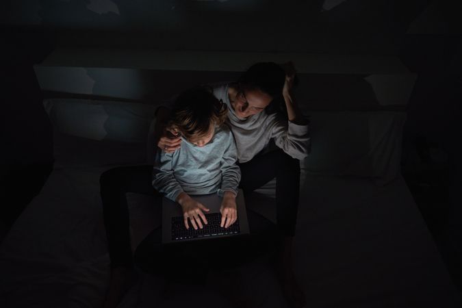 Mother helping son to do homework in darkness