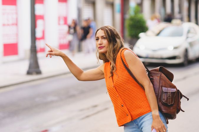 Young woman calling taxi on city street