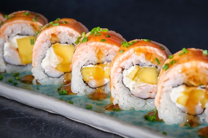 Close up of delicious uramaki sushi rolls with fresh salmon and sauce served on marble tray