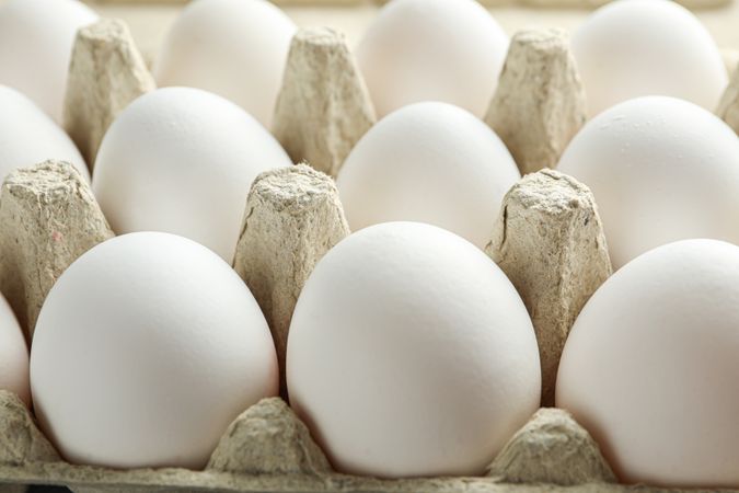 chicken eggs in carton box on wooden table, closeup