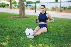 Woman working out arms with resistance band in park