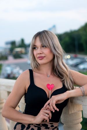 Beautiful young woman with red heart shaped lollipop