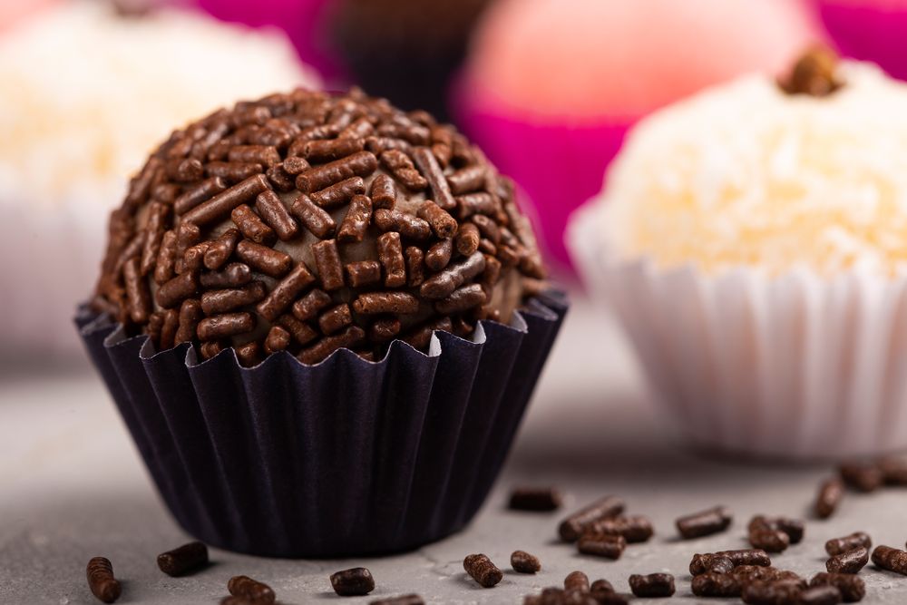 Close up of chocolate truffles with sprinkles and coconut truffles on marble table