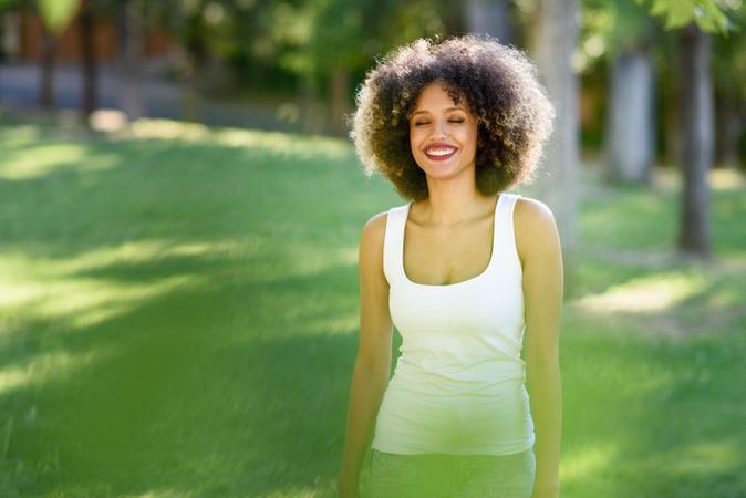 Carefree Black woman with afro hairstyle walking through park