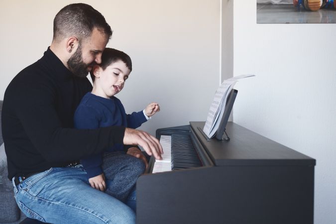 Father teaching son to play piano