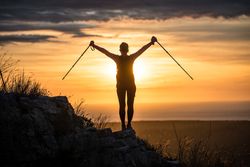 Silhouette of person with walking sticks in sunset