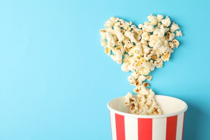 Popcorn heart and striped bucket on blue background, space for text