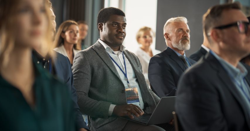 Corporate Delegate Using Laptop Computer While Listening to an Inspirational Entrepreneurship Presentation About Developing Markets.