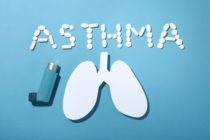 Asthma spelled in pills with lungs, inhaler and copy space