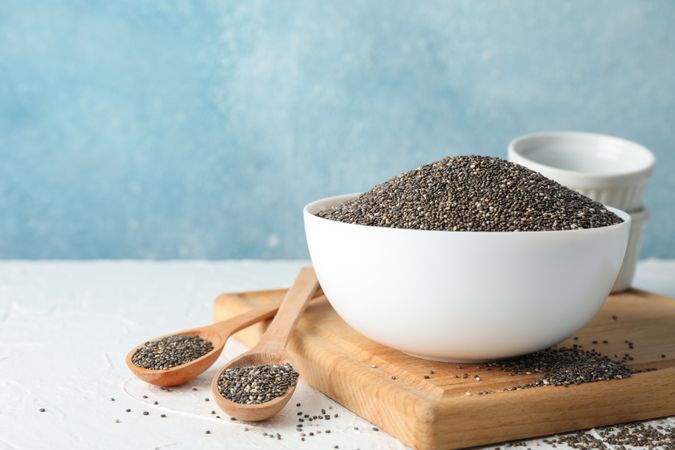 Bowl and spoons with chia on plain background, space for text