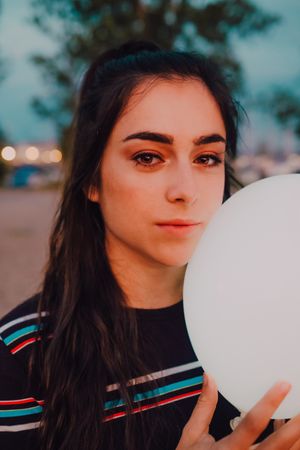 young female with white light balloon outside