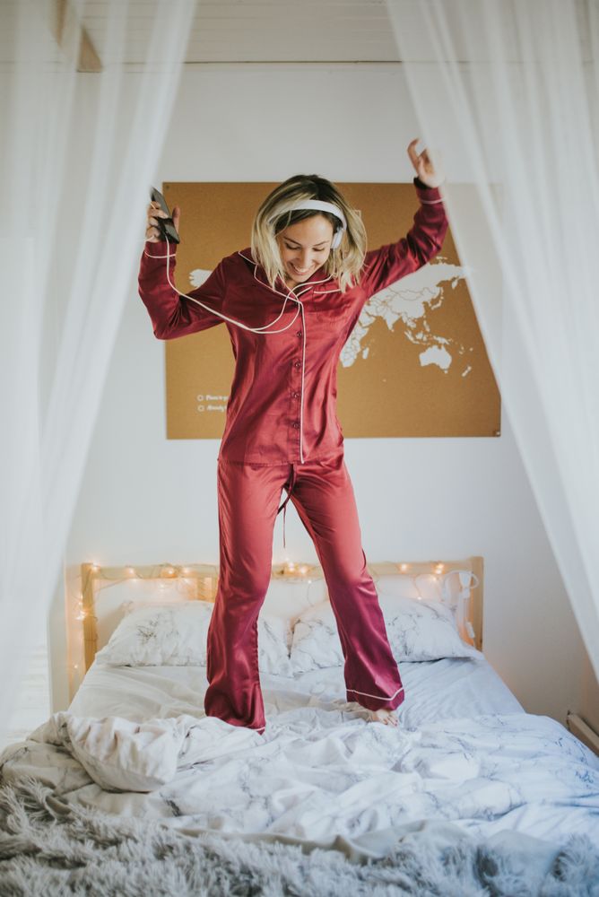 Woman with headphones dancing in bed